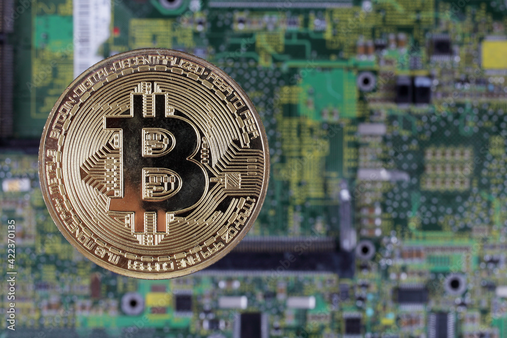 Golden bitcoin on the motherboard, selective focus, copy space.