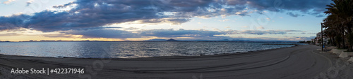 panorama of a scenic and colorful sunset over the ocean and silhouette of mountains on the shore behind