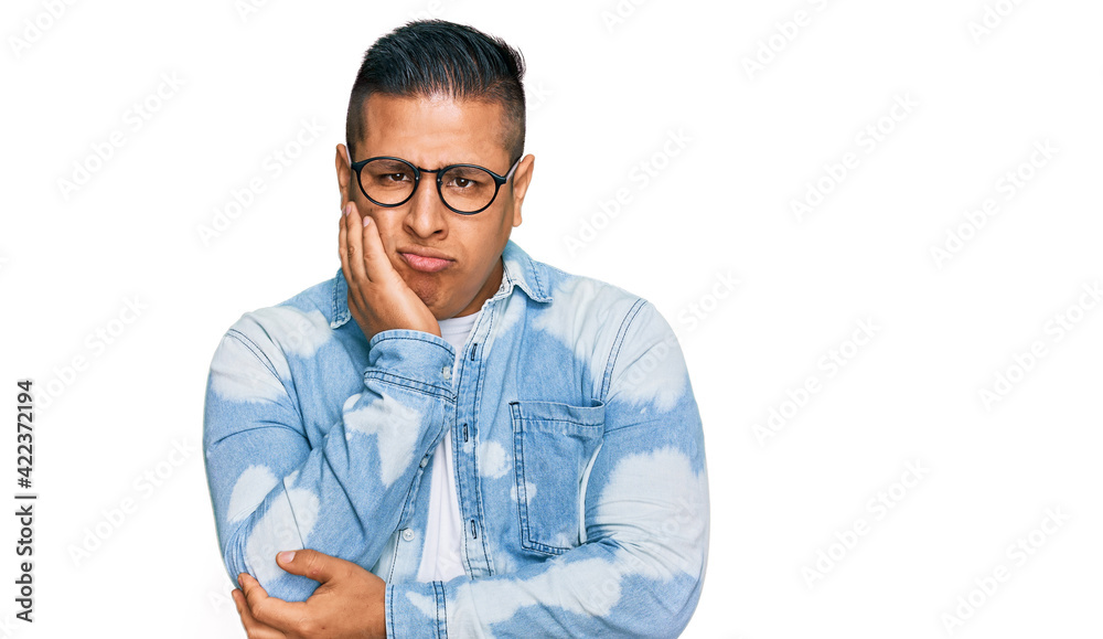 Young latin man wearing casual clothes and glasses thinking looking tired and bored with depression problems with crossed arms. Young latin man wearing casual clothes and glasses thinking looking tired and bored with depression problems with crossed arms.
