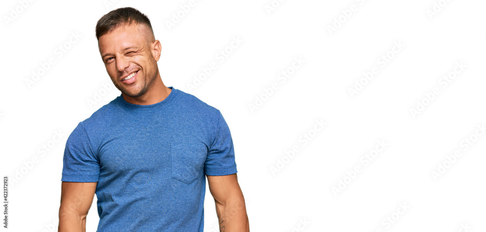 Handsome muscle man wearing casual clothes winking looking at the camera with sexy expression, cheerful and happy face. Handsome muscle man wearing casual clothes winking looking at the camera with sexy expression, cheerful and happy face.