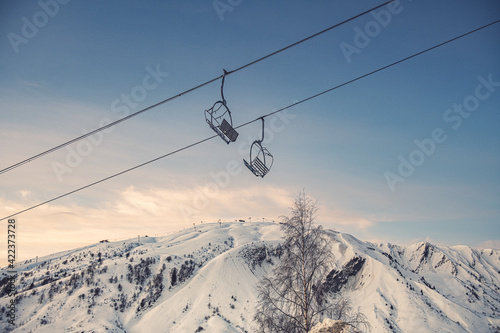 Deux telesieges vides sur fond de ciel bleu avec au fond la station de ski du Corbier