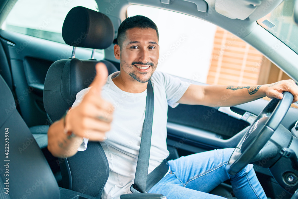 Young hispanic man smiling happy doing ok sign driving car. Young hispanic man smiling happy doing ok sign driving car.