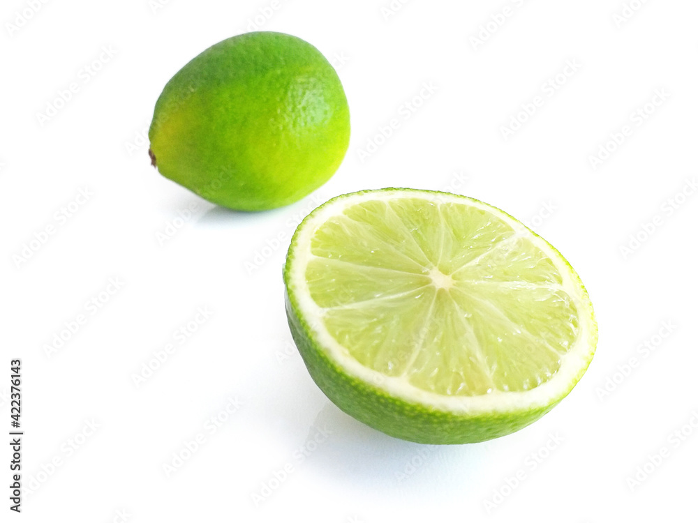 Perspective view of whole and half split lime on white background. Some pieces of a lime. Lemon cut in two. Tropical citrus fruit close up. Food and healthy eating concept. Perspective view of whole and half split lime on white background. Some pieces of a lime. Lemon cut in two. Tropical citrus fruit close up. Food and healthy eating concept.