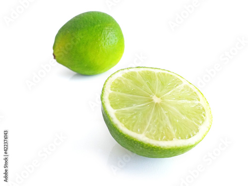 Perspective view of whole and half split lime on white background. Some pieces of a lime. Lemon cut in two. Tropical citrus fruit close up. Food and healthy eating concept.
