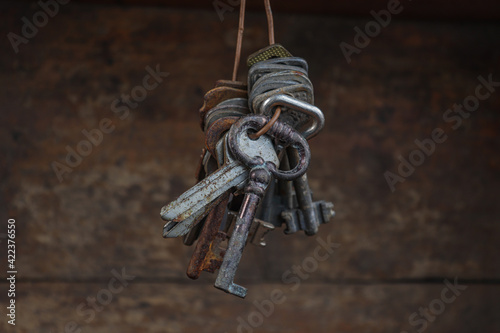 Bunch of vintage old keys from different locks. A lot of different old keys from different locks, hanging from the top on strings. Retro vintage brass keys on a wooden background.