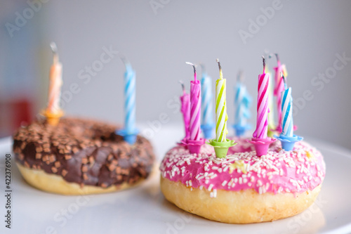 Colorful donuts with pink and chocolate icing with candles for birthday party.