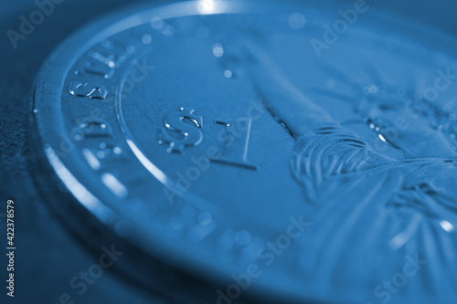 US one dollar coin close-up. Dark blue tinted background or wallpaper. American money, economy, finance or debt market. Background on an economic, business or financial topic. Macro