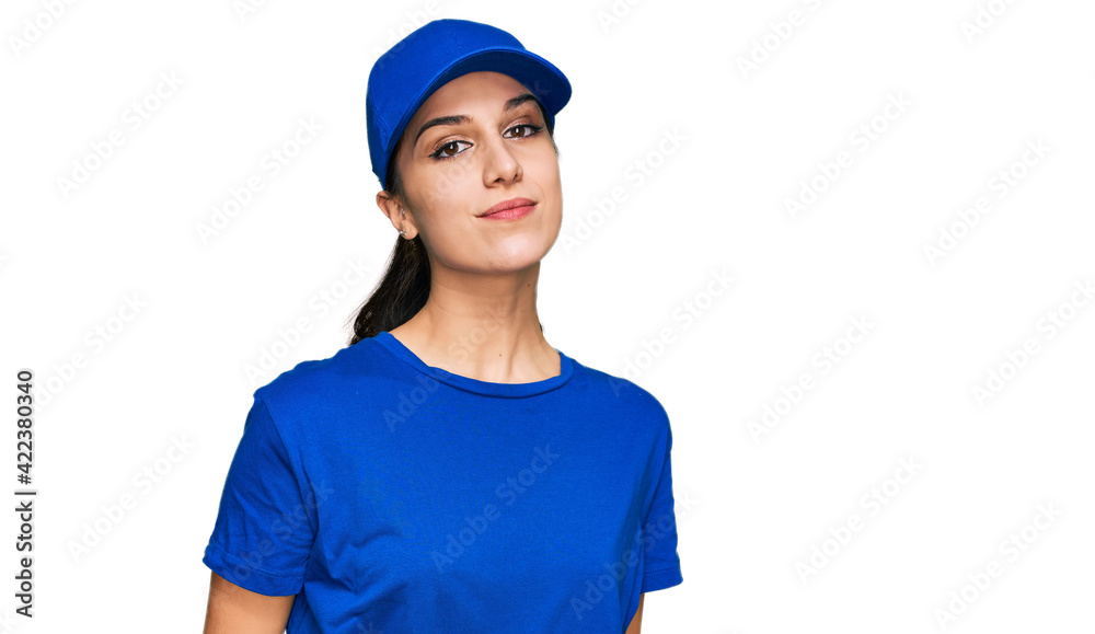 Young hispanic girl wearing delivery courier uniform relaxed with serious expression on face. simple and natural looking at the camera. Young hispanic girl wearing delivery courier uniform relaxed with serious expression on face. simple and natural looking at the camera.