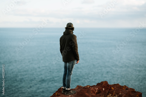 Schilderij op canvas Man with cap and black jacket looking at the ocean from a rock in Tenerife