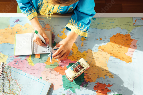 happy boy with blue djellaba takes notes in notebook next to world map