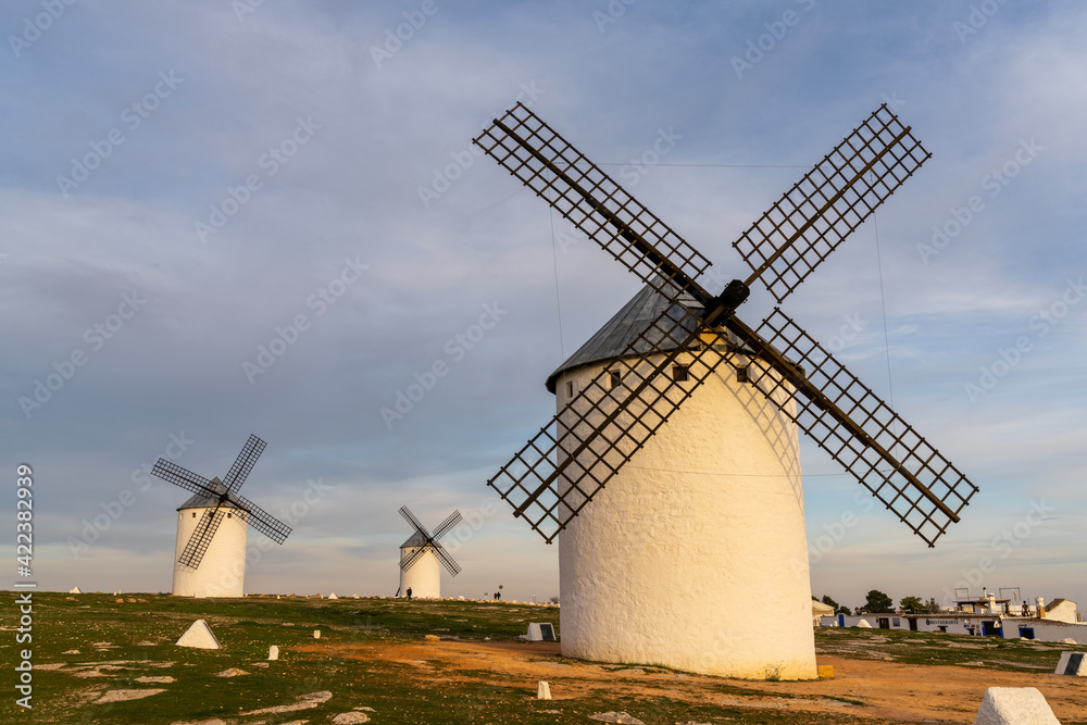 the historic white windmills of La Mancha above the town of Campo de Criptana in warm evening light