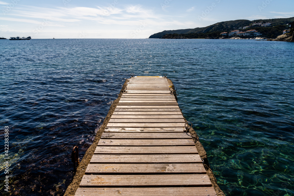 wood and concrete pier leading out into the clear refreshing waters of the Mediterranean Sea in a picturesque and peaceful cove