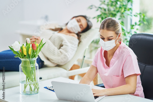 Professional psychiatrist consulting her patient and making notes both in masks