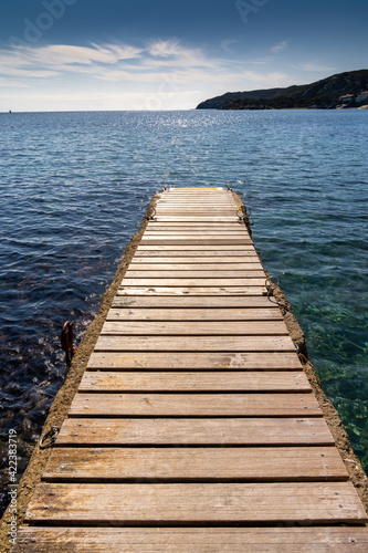 wood and concrete pier leading out into the clear refreshing waters of the Mediterranean Sea in a picturesque and peaceful cove © makasana photo