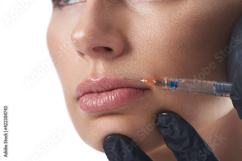 Close-up face of young woman receiving beauty injection for lip augmentation and lip contouring