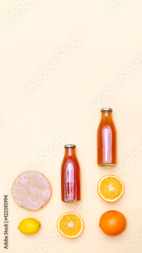 Vertical banner with two bottles of kombucha tea  scoby and citrus fruits for additional flavors on yellow pastel background with copy space. Orange  lemon. Healthy fermented drink. Flatlay mockup
