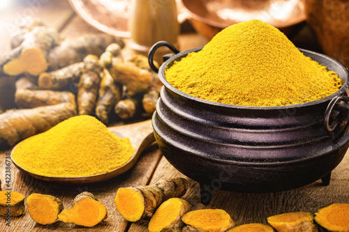 Turmeric powder in molten metal bowls on wooden table, spices, turmeric, turmeric root photo