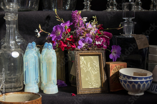 Four crystal virgins of Mary, wildflowers bouquet, glass decanter, embroidery frame for sale at Spitalfields market photo