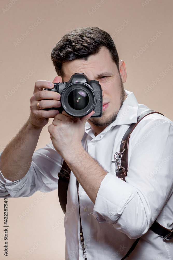 Close up portrait of photographer taking pictures with digital camera on brown background Close up portrait of photographer taking pictures with digital camera on brown background