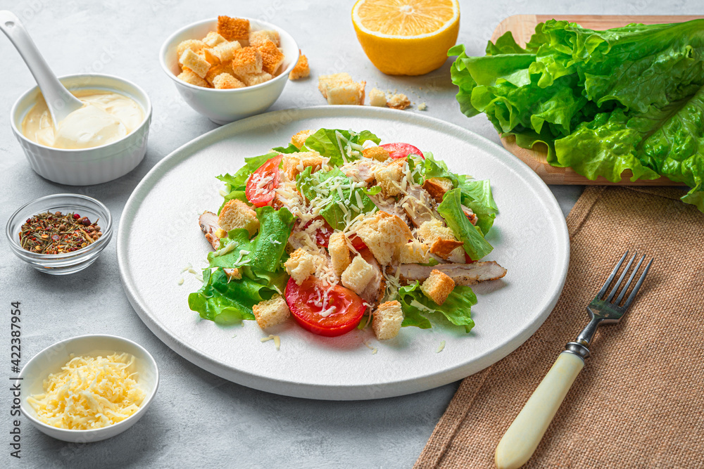 Fresh, delicious Caesar salad, sauce, cheese and lettuce on a gray background. Fresh, delicious Caesar salad, sauce, cheese and lettuce on a gray background.
