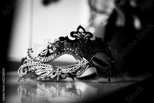 A black and white portrait of a mysterious venetian mask and its reflection on a marble windowsill to hide your identity at a masked ball, halloween party or carnaval.