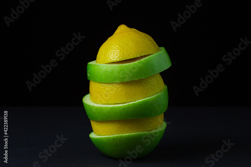 Green apple and lemon on a dark background. Sliced apple and lemon on a black background. Healthy food. Creative photo of fruit