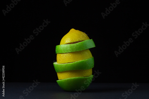 Green apple and lemon on a dark background. Sliced apple and lemon on a black background. Healthy food. Creative photo of fruit