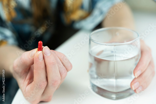 a pill and a glass of water in the girl's hand