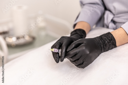 Doctor s hands in black glove with syringe.