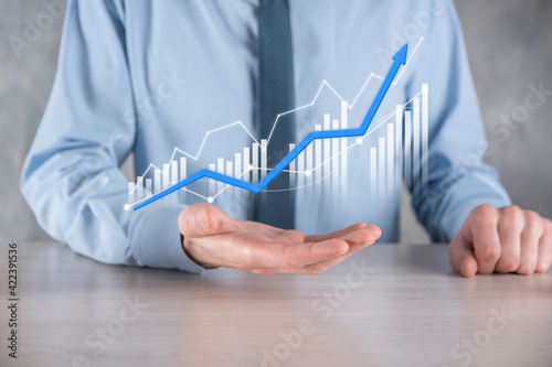 Businessman man holding a graph with positive profits growth. plan graph growth and increase of chart positive indicators in his business.more profitable and growing