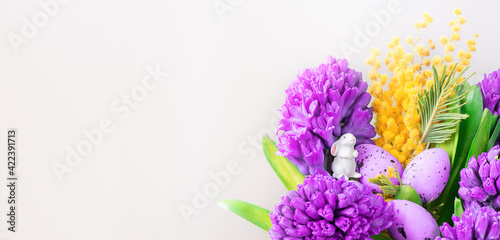 Colorful eastern bouquet with fresh spring flowers  cute bunny  violet eggs.