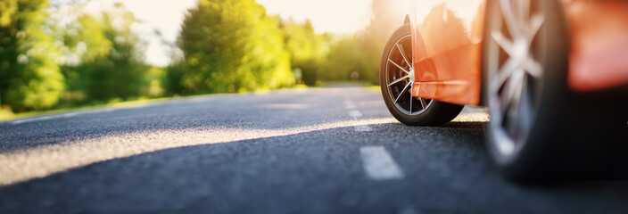 Red car on asphalt road in summer
