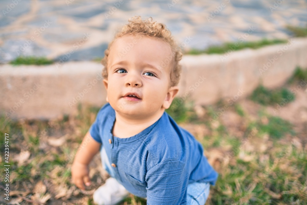 Cute and happy little boy having fun at the park on a sunny day. Beautiful blonde hair male toddler playing outdoors Cute and happy little boy having fun at the park on a sunny day. Beautiful blonde hair male toddler playing outdoors