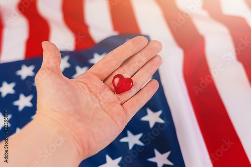 Hand with Souvenir of the Heart is on the American Flag. Expression of Patriotism for their Country, the United States. Love USA.