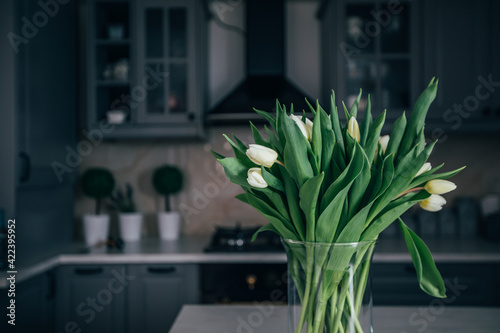 Vase of white tulips in a modern kitchen. Home concept with spring flowers.