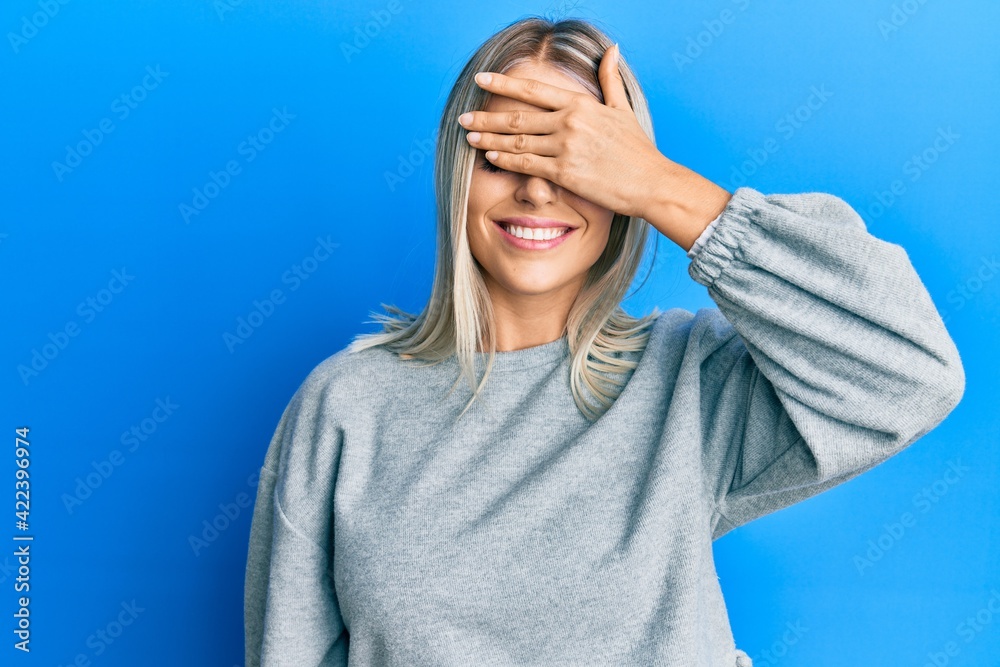 Beautiful blonde woman wearing casual clothes smiling and laughing with hand on face covering eyes for surprise. blind concept. Beautiful blonde woman wearing casual clothes smiling and laughing with hand on face covering eyes for surprise. blind concept.