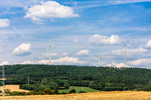 Sommerlandschaft mit Windkraftanlagen auf Berg vor attraktivem Wolkenhimmel photo