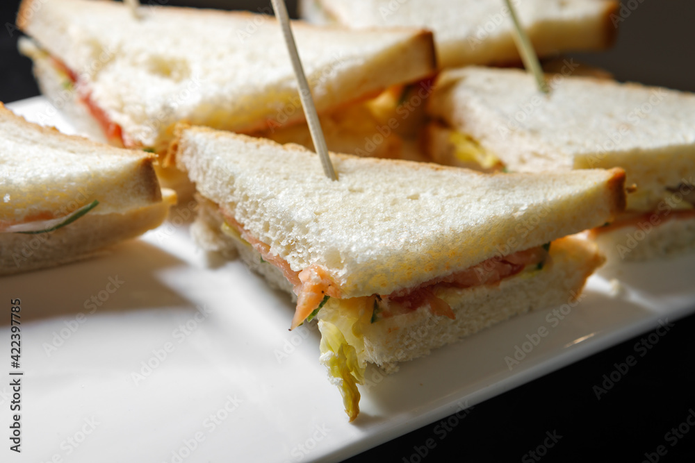 A plate of sandwiches on wooden skewers.