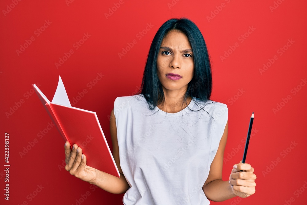 Young african american woman holding book and pencil skeptic and nervous, frowning upset because of problem. negative person. Young african american woman holding book and pencil skeptic and nervous, frowning upset because of problem. negative person.