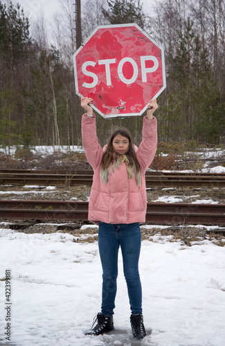 A young girl holds a road sign Stop, an expression of protest photo