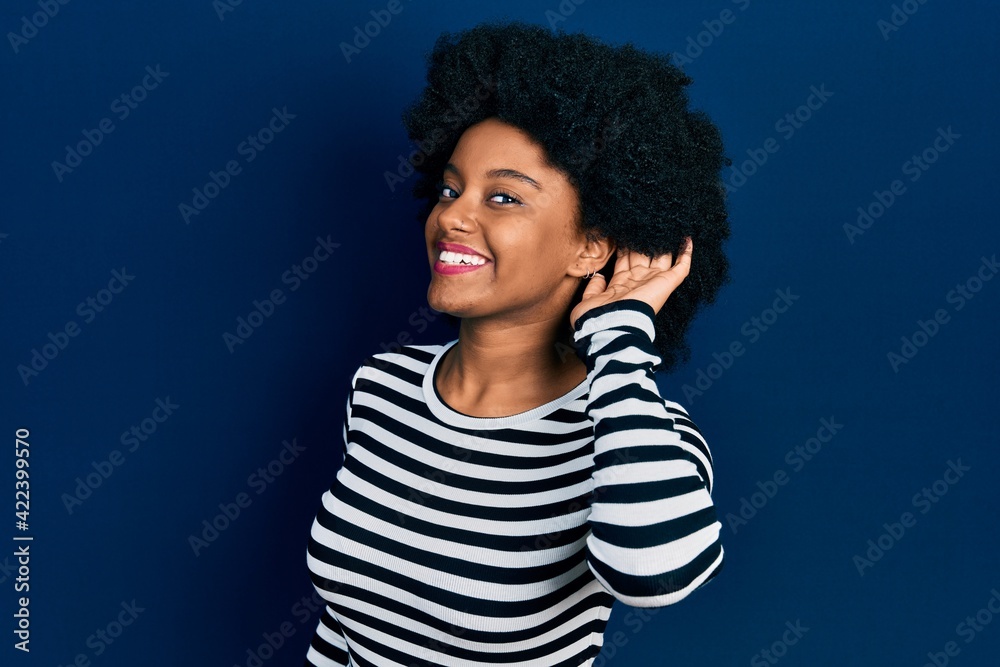 Young african american woman wearing casual clothes smiling with hand over ear listening an hearing to rumor or gossip. deafness concept. Young african american woman wearing casual clothes smiling with hand over ear listening an hearing to rumor or gossip. deafness concept.