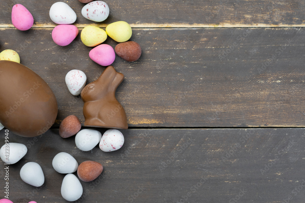 Colorful chocolate Easter eggs with rabbits on wooden vintage background.Top view with copy space for text.
