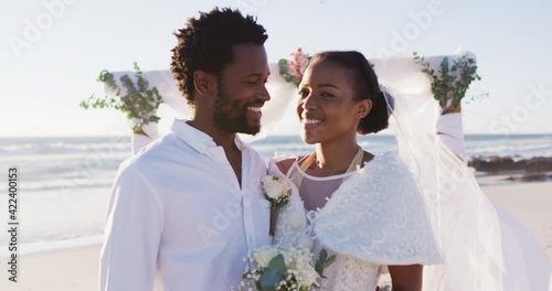 Portrait of african american couple in love getting married and smiling to camera on the beach photo