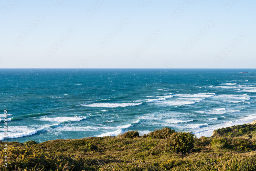 View over the blue ocean from a hill with green vegetation. Atlantic coast of France.