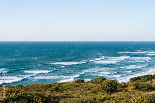 View over the blue ocean from a hill with green vegetation. Atlantic coast of France.