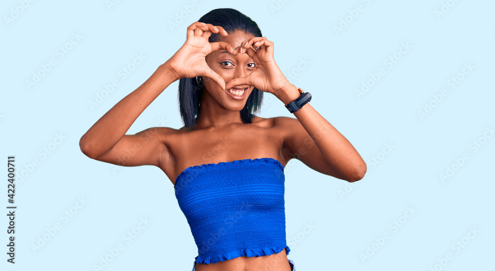 Young african american woman wearing casual summer clothes doing heart shape with hand and fingers smiling looking through sign Young african american woman wearing casual summer clothes doing heart shape with hand and fingers smiling looking through sign