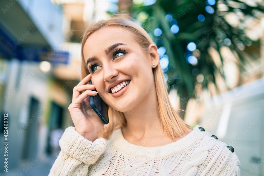 Young blonde girl smiling happy talking on the smartphone at the city. Young blonde girl smiling happy talking on the smartphone at the city.