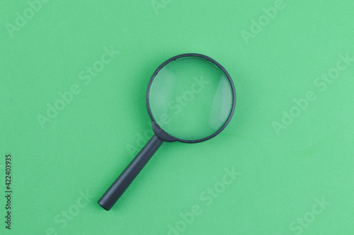 Top view of magnifying glass over green background