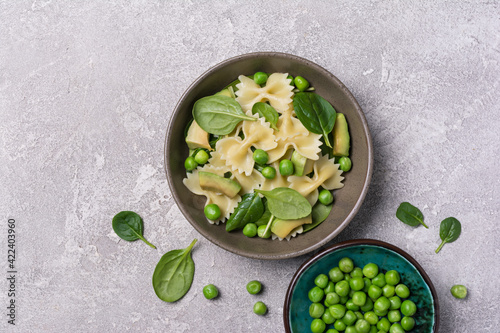 Farfalle pasta with green peas, avocado and spinach leaves