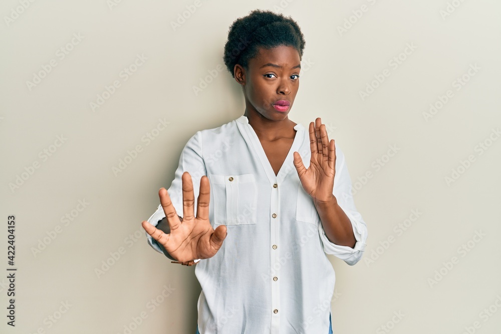 Young african american girl wearing casual clothes moving away hands palms showing refusal and denial with afraid and disgusting expression. stop and forbidden. Young african american girl wearing casual clothes moving away hands palms showing refusal and denial with afraid and disgusting expression. stop and forbidden.